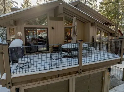 a house with a wrap around deck in the snow at The Lazy Bear Northstar Resort Truckee in Truckee
