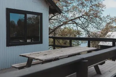 a wooden picnic table on a deck next to a building at Secluded rustic 2-bedroom cabin on private land in Miramonte