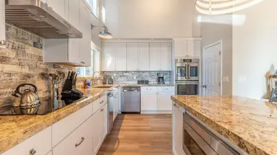 a kitchen with white cabinets and marble counter tops at Views Mins to Skiing Lake Incline Village Incline Serenity by AvantStay in Incline Village
