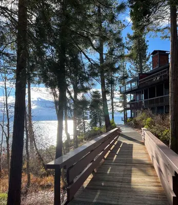 a wooden bench on a boardwalk next to the water at Chinquapin Condo Retreat - Walk to the Lake in Tahoe City