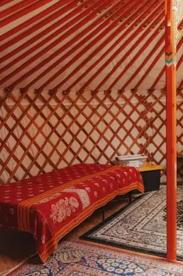 a bed in a room with a red blanket on it at Glamping yurt at nature retreat in Sequoia NForest in Miramonte
