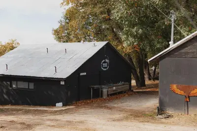 a black barn with a metal roof next to a building at Glamping yurt at a nature retreat Sequoia Highland in Miramonte