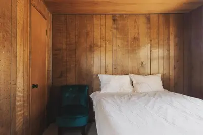 a bedroom with a bed and a green chair at Secluded rustic 3-bedroom cabin on private land in Miramonte