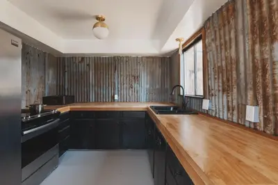 a kitchen with black cabinets and a wooden counter top at Spacious 4-bedroom cabin on secluded private land in Miramonte
