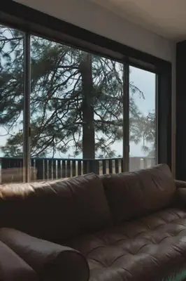 a couch in a living room with a large window at Secluded rustic 2-bedroom cabin at nature retreat in Miramonte