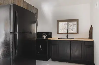 a kitchen with a black refrigerator and a counter at Secluded rustic 2-bedroom cabin at nature retreat in Miramonte