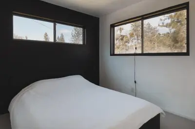 a bedroom with a white bed and two windows at Secluded rustic 2-bedroom cabin at nature retreat in Miramonte