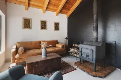 a living room with a couch and a wood stove at Secluded rustic 1-bedroom cabin on private land in Miramonte