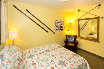 a bedroom with a bed and a mirror and a chair at Moderne Hostel in Mammoth Lakes