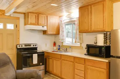 a kitchen with wooden cabinets and a black appliances at Hike, Ski and Sip Arnold Cabin 4 Mi to State Park! in Arnold