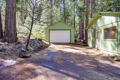 a green building with a garage in the woods at Stay Near Big Trees, Bring Your Pets Arnold Cabin in Arnold
