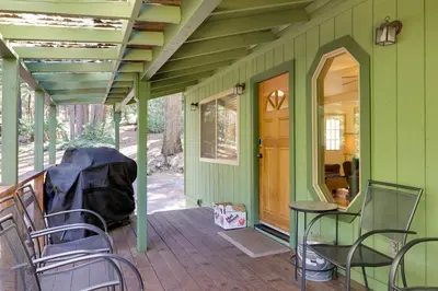 a green house with chairs and a table on a porch at Stay Near Big Trees, Bring Your Pets Arnold Cabin in Arnold