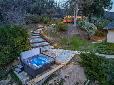 a backyard with a hot tub and a pathway at New Big Sky Cabin at Yosemite w/ VIEWS, hot tub, firepit, and more in Oakhurst