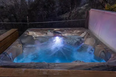 a hot tub in a backyard at night at New Big Sky Cabin at Yosemite w/ VIEWS, hot tub, firepit, and more in Oakhurst