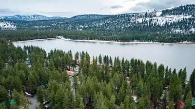 an aerial view of a lake with trees and mountains at Stylish Truckee Retreat Deck Near Lake Skiing Moraine by AvantStay in Truckee