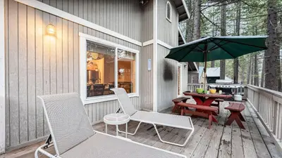 a patio with chairs and a table and an umbrella at Stylish Truckee Retreat Deck Near Lake Skiing Moraine by AvantStay in Truckee