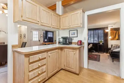 a kitchen with wooden cabinets and a living room at Lincoln Lodge cabin in Groveland