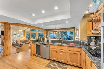 a kitchen with wooden cabinets and a living room at HCH1239 - Heavenly Tree House home in South Lake Tahoe