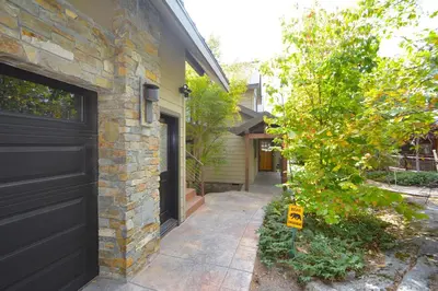 a house with a black garage door and a tree at Deer Lodge #1 Lake front in Bass Lake