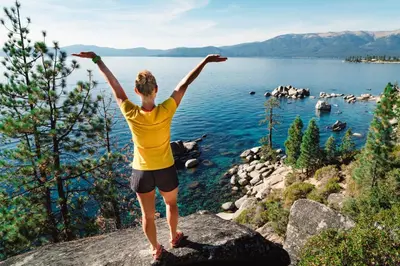 a person standing on a rock overlooking a body of water at Mountain Escape - Lake Tahoe - Incline Village - Private Garage in Incline Village