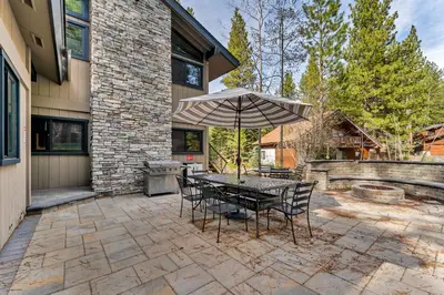 a patio with a table and chairs and an umbrella at Fire & Ice Spacious Retreat with Hot tub and Fireplace in Truckee