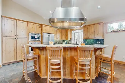 a kitchen with wooden cabinets and a large island with bar stools at The Tahoe Timber House in South Lake Tahoe