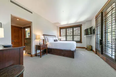 a bedroom with a bed and a desk and windows at Iron Horse Lodge South 302 by East West Hospitality in Truckee