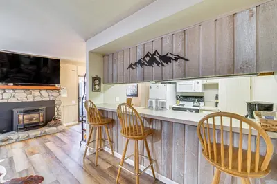a kitchen with a bar with chairs and a fireplace at Walk to Shops and Eats Mammoth Lakes Condo with Pool in Mammoth Lakes