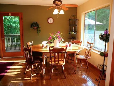 a dining room with a table and chairs and a clock at Gorgeous Cabin Rental with Spacious Furnished Deck in Pioneer, California in Pioneer