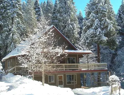 a log cabin in the snow with trees at Gorgeous Cabin Rental with Spacious Furnished Deck in Pioneer, California in Pioneer