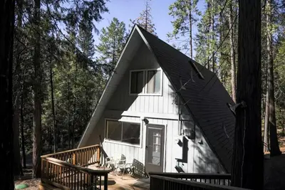 a tiny house in the woods with a porch at Stunning A-Frame Cabin Rental for Four Guests in Arnold, California in Arnold