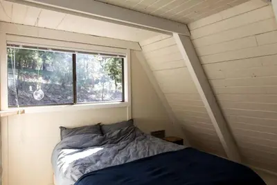 a bed in a small room with a window at Stunning A-Frame Cabin Rental for Four Guests in Arnold, California in Arnold