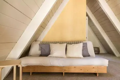 a couch in the attic of a house at Stunning A-Frame Cabin Rental for Four Guests in Arnold, California in Arnold