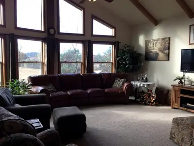 a living room with a brown couch and windows at Luxury Cabin Rental with a Fire Pit in Coulterville, California in Coulterville