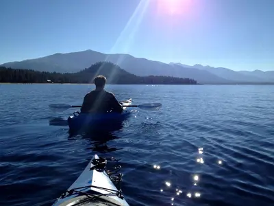 a man in a kayak on a large body of water at Traditional Log Cabin Rental for Couples on the West Shore of Lake Tahoe, California in Tahoe City