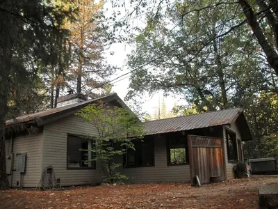 a small house in the woods with leaves around it at Country Cabin with Spa Hot Tub and Private Deck near Rollins Lake in California in Gold Run