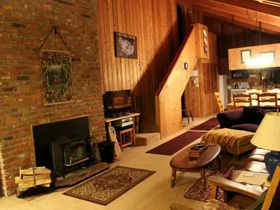 a living room with a fireplace and a brick wall at Country Cabin with Spa Hot Tub and Private Deck near Rollins Lake in California in Gold Run