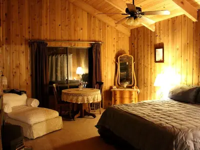 a bedroom with a bed and a table and a fan at Country Cabin with Spa Hot Tub and Private Deck near Rollins Lake in California in Gold Run