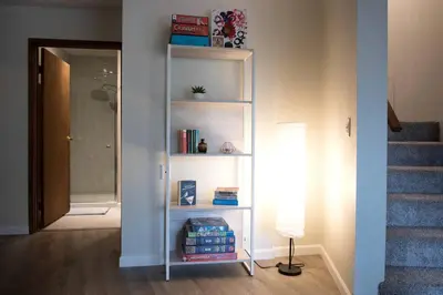 a white book shelf in a hallway with a staircase at Secluded Dome Rental Surrounded by Stunning Nature near Arnold, California in Arnold