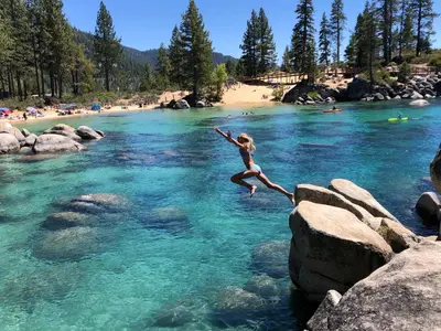 a woman jumping off rocks into a river at First level studio Unit #7 close to everything bike, ski, swim Zephyr Cove! in Zephyr Cove