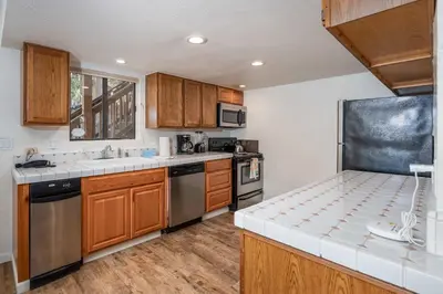 a kitchen with wooden cabinets and stainless steel appliances at Yosemite Aviary and Quail Within Yosemite - 2 Separate Family Units Welcoming Up To 14 Guests in Yosemite West