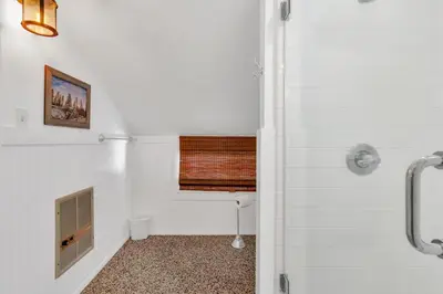 a white bathroom with a toilet and a window at CC Cabin - Full Game Room & Wrap Around Deck in Shaver Lake