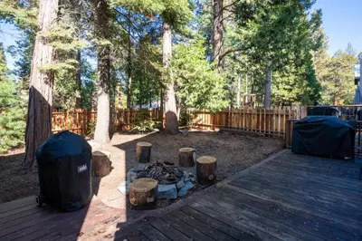 a backyard with a campfire and a wooden deck at A Tuscan Adventure in California 3 BDR Sleeps 8 in Shaver Lake
