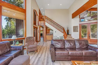 a living room with leather furniture and a staircase at Gorgeous 5 BDR Traviloli Mountain Retreat for 10 in Shaver Lake