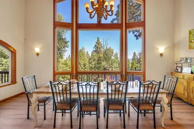a dining room with a table and chairs and windows at Gorgeous 5 BDR Traviloli Mountain Retreat for 10 in Shaver Lake
