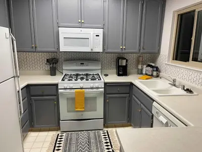 a kitchen with gray cabinets and a stove and a microwave at Cavu Cabin - A Classic Mountainside Escape in Shaver Lake