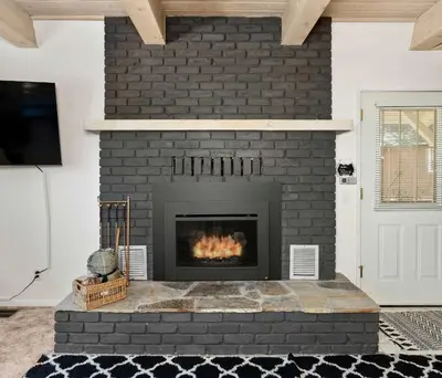 a living room with a black brick fireplace at Cavu Cabin - A Classic Mountainside Escape in Shaver Lake