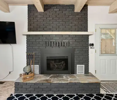 a living room with a black brick fireplace at Cavu Cabin - A Classic Mountainside Escape in Shaver Lake