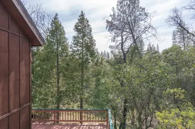 a view from the side of a house with a fence and trees at Happy Days Retreat with Private Pool in Bass Lake Annex