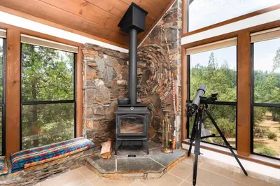 a stone fireplace in a room with windows at Happy Days Retreat with Private Pool in Bass Lake Annex